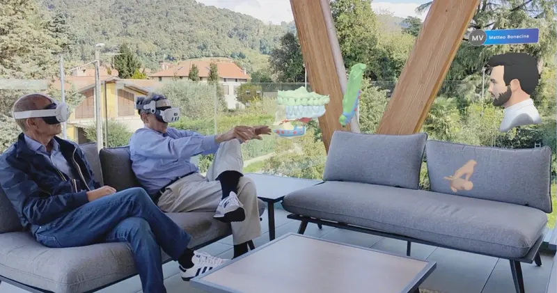 Two clinicians wearing mixed reality headsets review 3D dental models and a remote colleague's avatar in a shared HoloDentist session